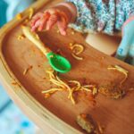 person holding brown wooden tray with green leaf